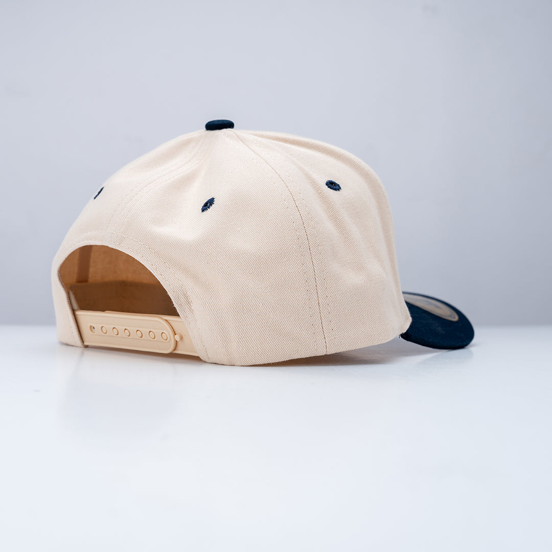 Beige cap with black embroidered details on a white background