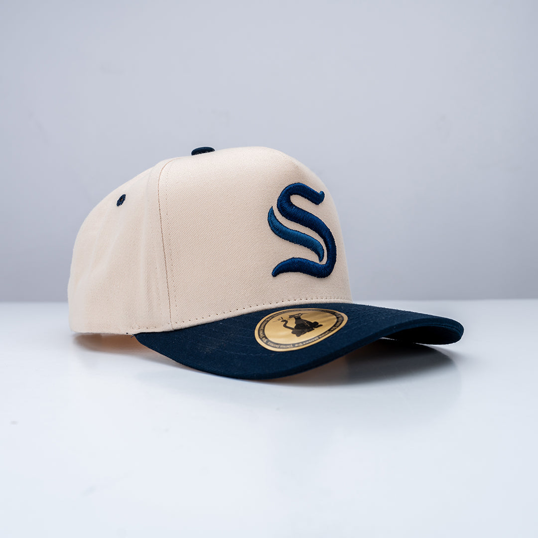 Beige and navy baseball cap with logo on a light gray background